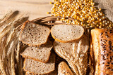 Fototapeta Kuchnia - The shop counter is decorated with various types of wheat and rye bread and ears of ripe rye and wheat. Thin slices of bread.