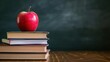 Stacking books with a red apple in the classroom in front of black board