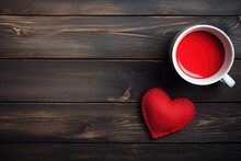A Cozy Setting With A Red Fabric Heart And A Cup Of Red Tea On A Dark Wooden Background, Evoking Warmth. Romantic Heart And Red Tea On Wooden Table