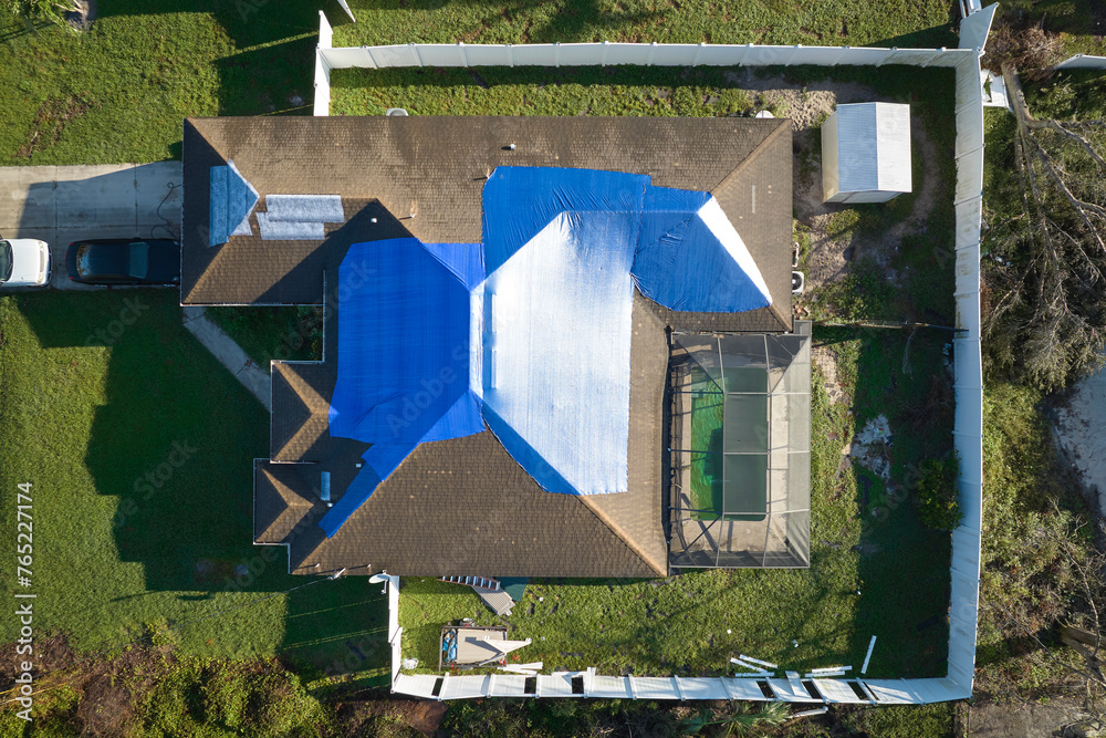 Top view of leaking house roof covered with protective tarp sheets