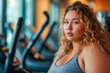 Portrait of an overweight woman in a sports gym, against the background of exercise equipment, weight loss concept, obesity problem. Copy space