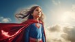 Superhero child girl with red cape and flying hair over sky background.