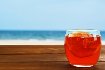 Poster - Aperol spritz cocktail with orange slice on wooden table at beach. Space for text