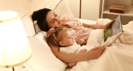 Poster - Mother and little baby reading book in bed