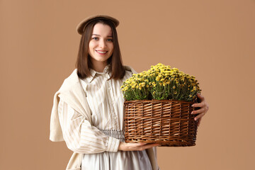 Sticker - Young woman with chrysanthemum flowers on beige background