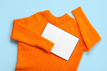 Wall Mural - Warm female sweater and open notebook on color background