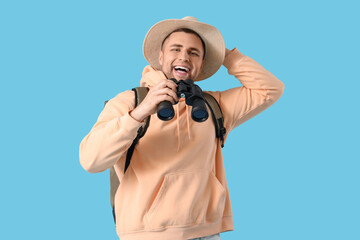 Canvas Print - Male tourist with backpack and binoculars on blue background