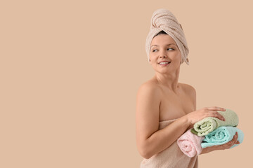 Canvas Print - Young woman with towels after shower on beige background