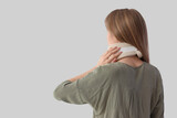 Fototapeta  - Injured young woman with cervical collar after accident on light background, back view