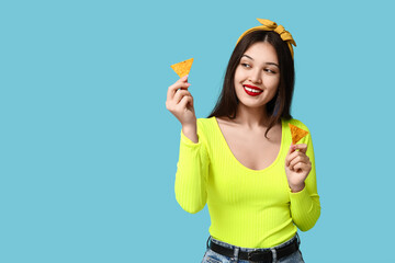 Poster - Portrait of young woman with tortilla chips on blue background. National Tortilla Chip Day celebration