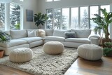 Fototapeta  - A spacious, snowy view through large windows complementing a modern white sofa and soft pouffes in a clean living room.