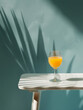 Glass of fresh orange juice on table with background wall and shade of tropical leaves. Travel drinks background.