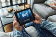 © Keitma - Buy stocks online concept image with a person holding a tablet with word Buy on screen representing an investor buying stocks or goods on the web from home