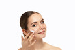 Skin Care. Woman Applying Facial Cream On Beauty Face Closeup. Smiling Girl Model With Natural Makeup Using Moisturizer, Cosmetic Product.