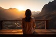 Woman sits on wooden bench overlooking mountain range