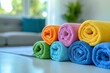Roll up of multiple color towels on white table with copy space on blurred living room background