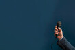 main tenant un microphone, ou micro d'un homme portant un costume et une chemise. Fond bleu canard foncé (teal)  avec espace négatif copy space. Droit de parole, liberté de la Presse