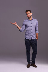 Poster - Happy man, portrait and advertising with palm for marketing, presentation or showcase on a gray studio background. Young and handsome male person or employee with smile showing option on mockup space