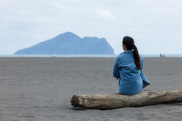 Wall Mural - Woman sit on the beach and look at the Guishan at Yilan