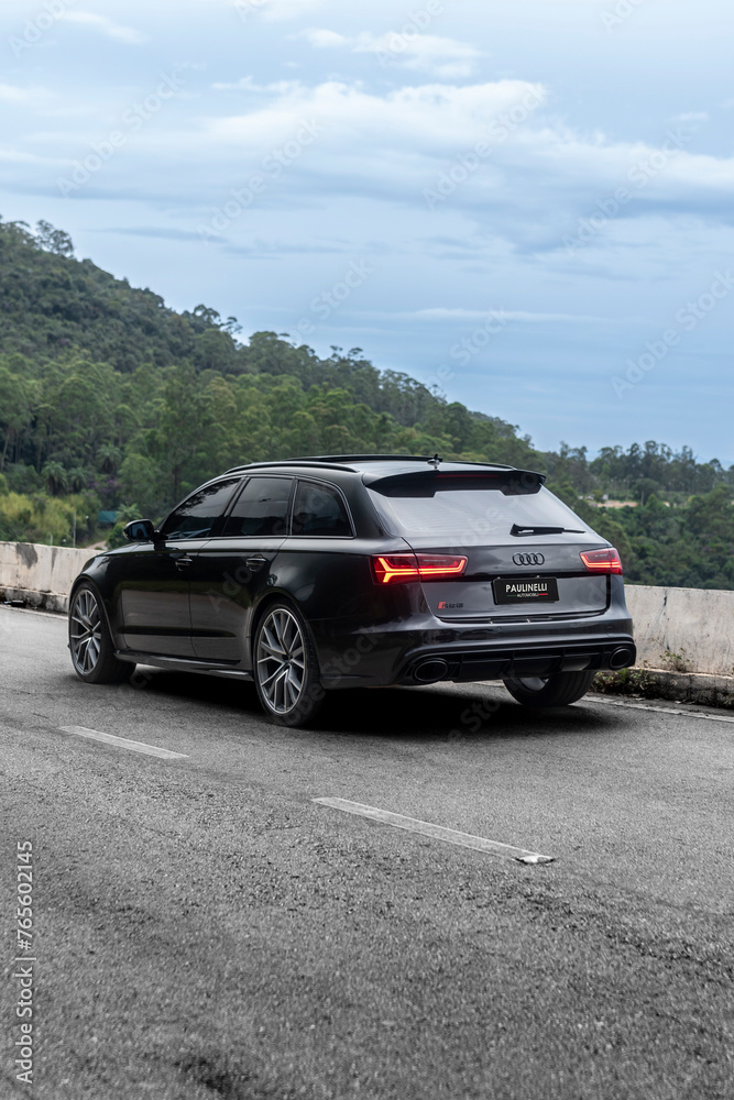 Black Audi RS6 Avant rear end three quarters view on empty road in the ...