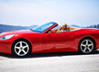 © ArcursJointTeam/peopleimages.com - Woman, red sports car and relax on road trip, travel and luxury transport on summer drive. Happy female person, holiday and countryside wellness on mountain street, vacation and adventure in vehicle