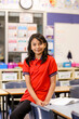 © Austockphoto - Female student sitting on a desk in a classroom smiling