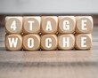Cubes, blocks or dice with the german words for 4 day week - 4 Tage Woche on wooden background