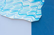 paper with blue wavy lines and abstractly cut edge on paper with two very different surface textures