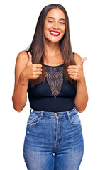 Wall Mural - Young hispanic woman wearing casual clothes success sign doing positive gesture with hand, thumbs up smiling and happy. cheerful expression and winner gesture.