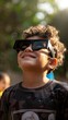 A young boy wearing protective glasses is watching the solar eclipse.