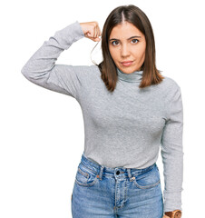 Poster - Young beautiful woman wearing casual turtleneck sweater strong person showing arm muscle, confident and proud of power