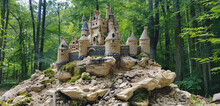 A Verdant Forest Encircles A Charming Little Castle Set Atop A Rocky Hill