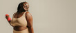 © gstockstudio - Confident plus size African woman in sportswear exercising with dumbbells on studio background