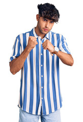 Sticker - Young hispanic man wearing casual clothes ready to fight with fist defense gesture, angry and upset face, afraid of problem