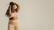 © gstockstudio - Full Length of beautiful African plus size woman in sportswear adjusting her dreadlocs on studio background