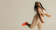 © gstockstudio - Full length happy plus size African woman in sportswear dancing on studio background