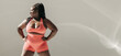 © gstockstudio - Full length of happy African plus size woman in sportswear warming up before training in fitness studio