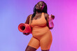 © gstockstudio - Active young voluptuous woman in sportswear carrying exercise mat and smiling on pink background