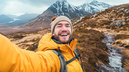 Poster - A man in a yellow jacket is smiling and taking a selfie. He is wearing a white hat and has a backpack on. Concept of adventure and excitement, as the man is enjoying his time outdoors in the mountains