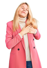 Wall Mural - Young beautiful blonde woman wearing elegant clothes smiling with hands on chest with closed eyes and grateful gesture on face. health concept.