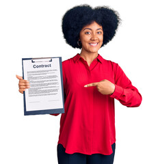 Poster - Young african american girl holding clipboard with contract document smiling happy pointing with hand and finger