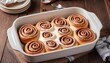baked sweet Cinnabon with cream in a baking dish on white background