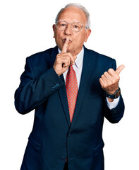 Wall Mural - Senior man with grey hair wearing business suit and glasses asking to be quiet with finger on lips pointing with hand to the side. silence and secret concept.