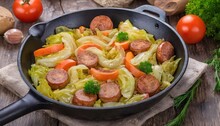 Cooked Fried Cabbage With Vegetables And Sausages, In A Frying Pan