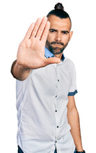 Hispanic Man With Ponytail Wearing Casual White Shirt Doing Stop Sing With Palm Of The Hand. Warning Expression With Negative And Serious Gesture On The Face.