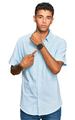 Wall Mural - Young handsome african american man wearing casual clothes in hurry pointing to watch time, impatience, looking at the camera with relaxed expression