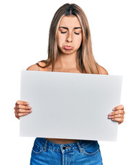 Canvas Print - Hispanic young woman holding blank empty banner depressed and worry for distress, crying angry and afraid. sad expression.