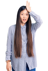 Sticker - Young beautiful chinese woman wearing casual shirt surprised with hand on head for mistake, remember error. forgot, bad memory concept.