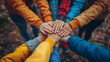 © SnapVault - A diverse group of children's camp counselors stack hands together in a show of unity and teamwork, against a blurred autumn background. School activities in nature, environmental education.