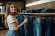 Attraktive junge Frau beim Jeanskauf in einem trendigen Bekleidungsgeschäft